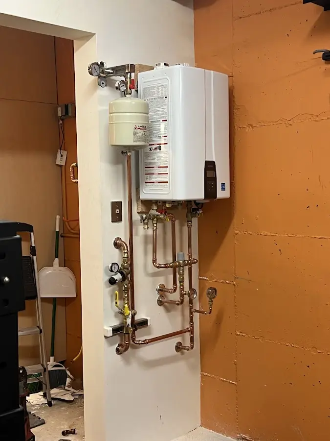 Plumbing technician inspecting water heater connections in Sherburne